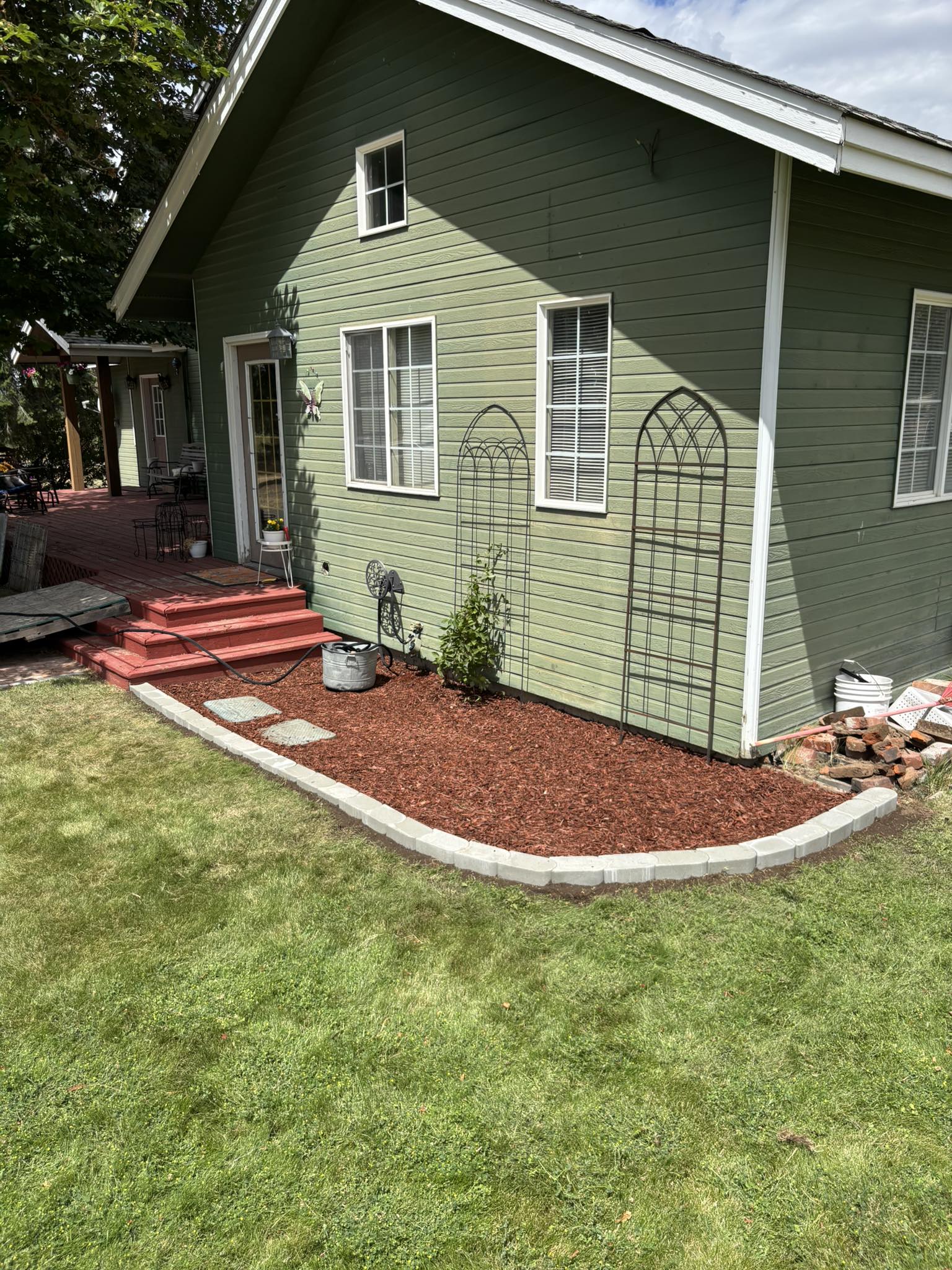 Fresh mulch garden bed with curved stone edging beside a green lawn