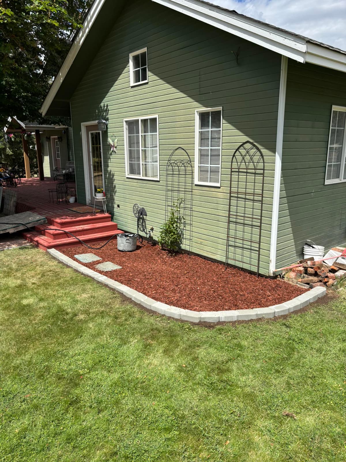 Fresh mulch garden bed with curved stone edging beside a green lawn